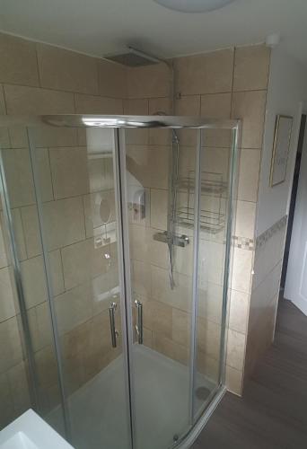 a shower with a glass door in a bathroom at Moore Apartment in Bourton on the Water
