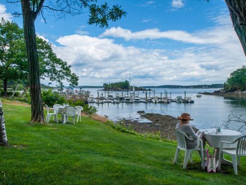 a person sitting at a table on the grass by the water at Inn at Diamond Cove in Portland