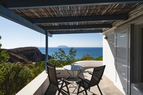a patio with a table and chairs and the ocean at Apollon Village Hotel in Anafi
