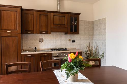 a kitchen with wooden cabinets and a table with flowers on it at Agriturismo Stovali Da Lustrinu in Protte