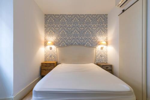 HOMEABOUT DIEGO DE LEÓN Apartment I في مدريد: سرير في غرفة مع مصباحين على الحائط