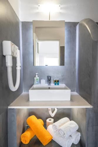 a bathroom with a sink and a mirror and towels at Apollon Village Hotel in Anafi