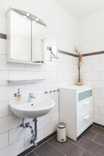 a white bathroom with a sink and a mirror at Skerra Apartments "am Fitness-Studio" in Fehmarn