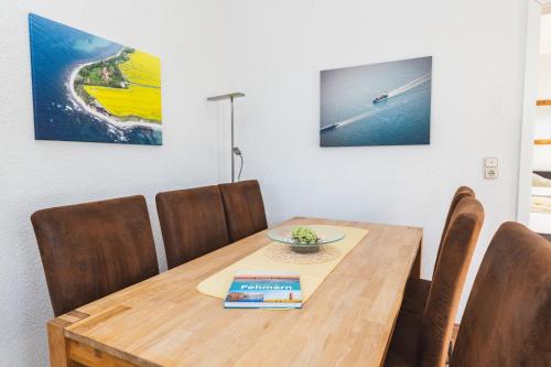 a dining room table and chairs with a wooden table and a book at Skerra Apartments "am Fitness-Studio" in Fehmarn