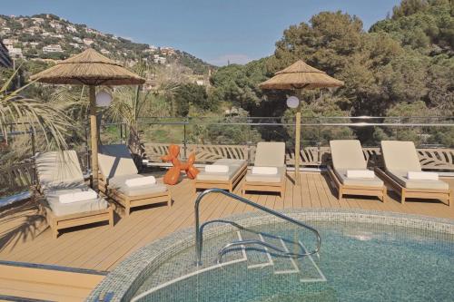 a deck with a swimming pool and chairs and a swimming poolvisor at Casa Coco Boutique Hotel & Spa 4*S - Adults Only in Lloret de Mar