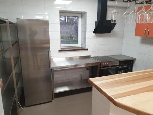 a kitchen with a stainless steel refrigerator and a window at Apgyvendinimas Rusnėje, šalia Pakalnės upė 100m in Rusnė