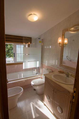 a bathroom with a tub and a toilet and a sink at Playa de Cesantes in Pontevedra
