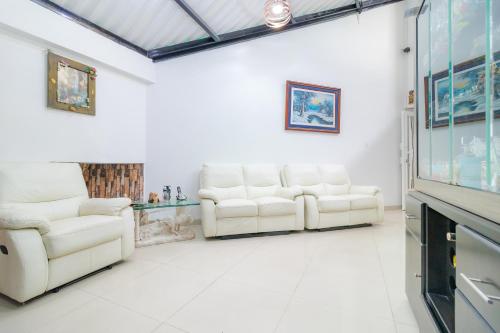 a living room with two white chairs and a flat screen tv at Casa Hotel Quinta Real in Bogotá