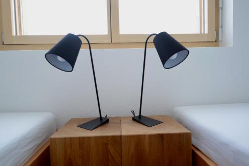 two black lamps on a wooden table next to two beds at Alpen-Park 2. Stock West in Riederalp