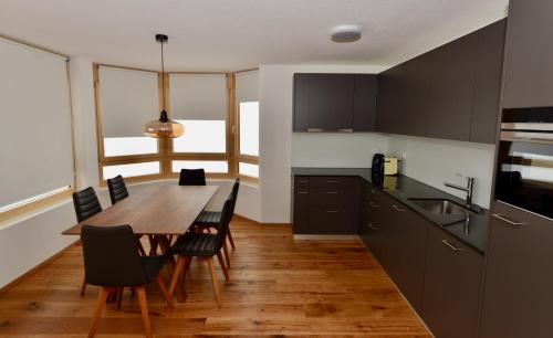 a kitchen with a wooden table and chairs and a dining room at Alpen-Park 2. Stock West in Riederalp