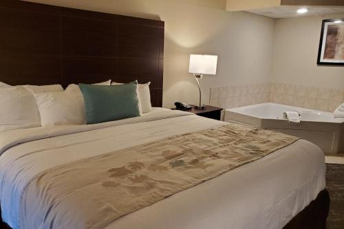 a hotel room with a bed and a bath tub at Cobblestone Suites - Oshkosh in Oshkosh