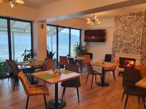 a restaurant with tables and chairs and a fireplace at Pensiunea Sunshine in Eşelniţa