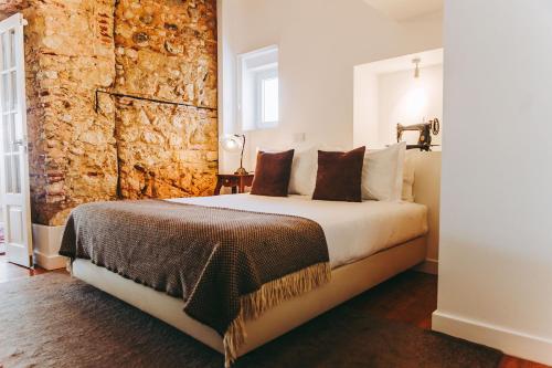 1 dormitorio con 1 cama grande y pared de piedra en 54 Santa Catarina Apartments, en Lisboa