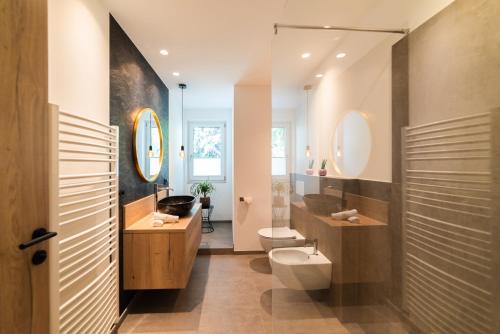 ein Bad mit einem WC, einem Waschbecken und Spiegeln in der Unterkunft Marlingsuites in Marling