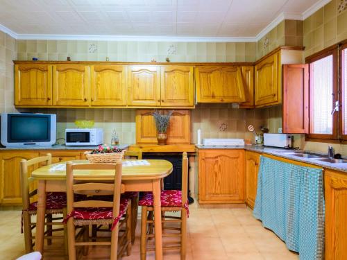 Holiday Home Hostalas by Interhome في Rosell: مطبخ بدولاب خشبي وطاولة مع كراسي