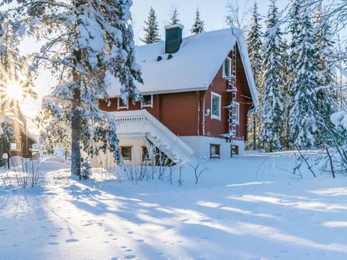 uma casa vermelha na neve com árvores cobertas de neve em Holiday Home Kulma-alpit a paritalon yläk by Interhome em Hyrynsalmi