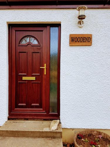 a wooden door to a house with a sign on it at Self catering upper floor flat at Woodend house in Balmacara