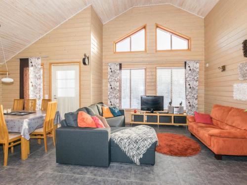a living room with a couch and a table and a television at Holiday Home Rinteenkotka cottage by Interhome in Hyrynsalmi