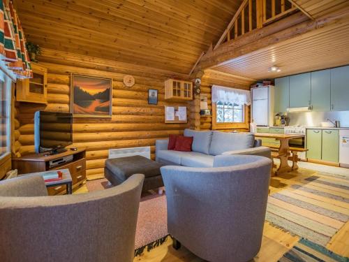 ein Wohnzimmer mit einem Sofa und Stühlen sowie eine Küche in der Unterkunft Holiday Home Metsätähti by Interhome in Kotila