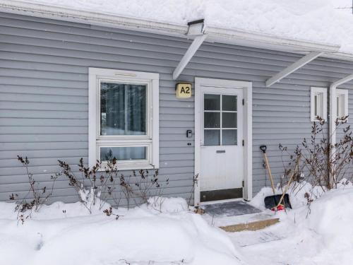a gray house with a white door in the snow at Holiday Home Kotipaljakka a2 by Interhome in Kotila
