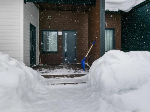 ein Schneehaufen vor einem Haus mit einer Schaufel in der Unterkunft Holiday Home Skivillas paljakka 4- - 2 bedrooms by Interhome in Kotila