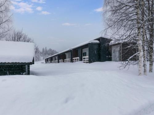 Holiday Home Skivillas paljakka 4- - 2 bedrooms by Interhome في Kotila: مبنى مغطى بالثلج بجانب كومة من الثلج