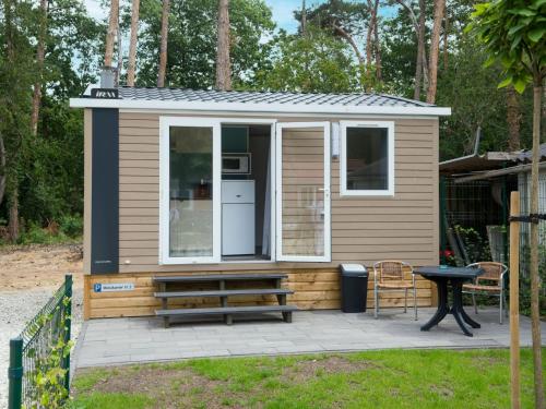 a tiny house with a bench and a table at Holiday Home De Brenkberg-1 in Schinveld