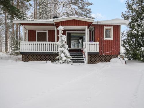 una casa roja en la nieve con un patio cubierto de nieve en Holiday Home Ahven by Interhome, en Hiukkajoki