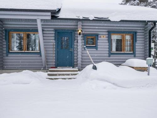 ein Haus mit einer blauen Tür im Schnee in der Unterkunft Holiday Home Karhunpesä c by Interhome in Kotila