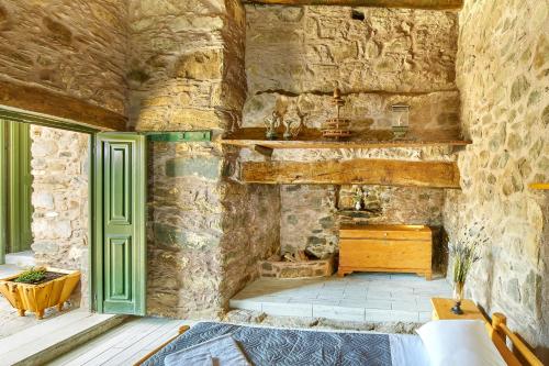 Cette chambre est dotée d'un mur en pierre et d'une cheminée. dans l'établissement Authentic Cottage in a heaven of natural Beauty, à La Canée