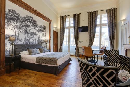 a bedroom with a bed and a desk and chairs at La Villa des Consuls - Gîte de tourisme de charme in Sarlat-la-Canéda