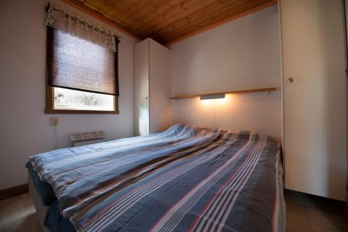 1 dormitorio con 1 cama en una habitación con ventana en Björnbyn Stugby en Råda