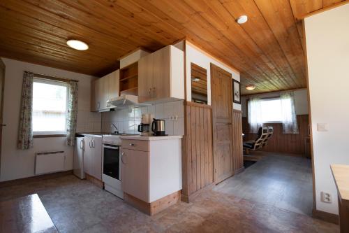 cocina con electrodomésticos blancos y techo de madera en Björnbyn Stugby, en Råda