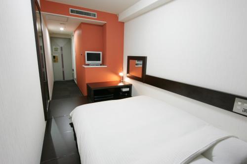 a bedroom with a white bed and orange walls at Green Rich Hotel Suizenji in Kumamoto