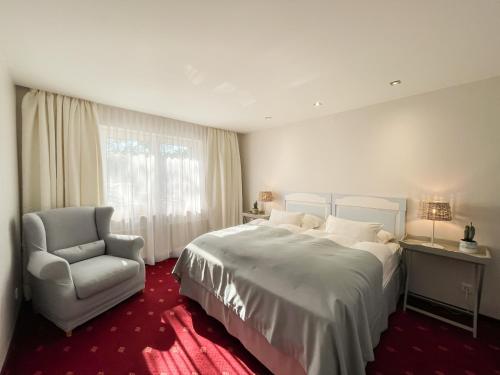 a bedroom with a large bed and a chair at Willa Mandala in Dziwnówek
