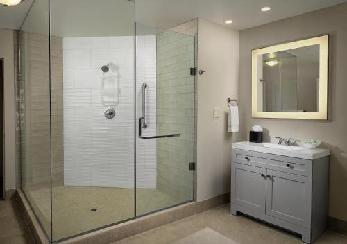 a bathroom with a glass shower and a sink at Inn at Morro Bay in Morro Bay