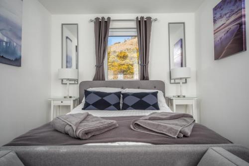 a bedroom with a bed with two lamps and a window at Rona@Knock View Apartments, Sleat, Isle of Skye in Teangue