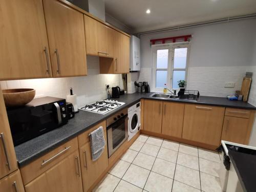 a kitchen with wooden cabinets and a stove top oven at Large modern GF 1-bed apartment Sleeps 2 in London