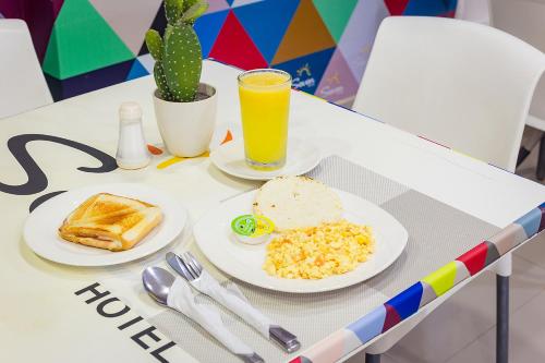 a table with plates of food and a glass of orange juice at Hotel Seven Monteria in Montería