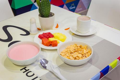 a table with bowls of fruit and a bowl of milk at Hotel Seven Monteria in Montería