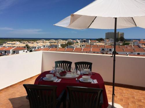 un tavolo con sedie e un ombrellone su un balcone di Alagoa Praia Altura - Prestige for Home ad Altura