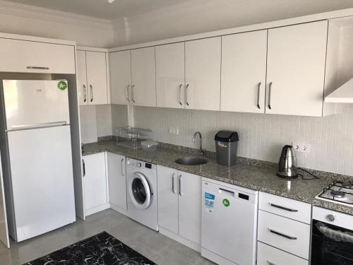 a kitchen with white cabinets and a washer and dryer at Kemer Guney Homes Apart in Kemer