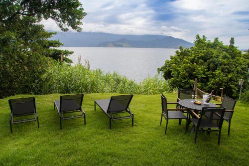 a table and chairs on the grass near a lake at Wyndham Ilhabela Casa Di Sirena in Ilhabela