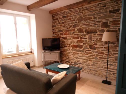 sala de estar con pared de ladrillo y sofá en Gite de charme Les Buissonnets, en Plesder