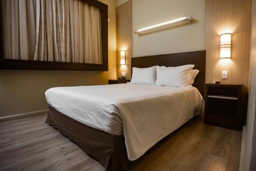 a bedroom with a large bed with white sheets and pillows at Master Cosmopolitan Moinhos de Vento in Porto Alegre