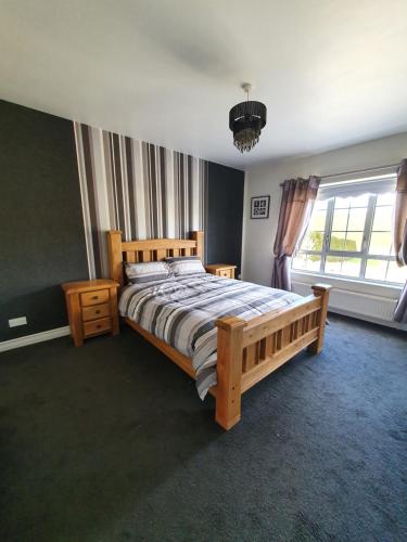 a bedroom with a wooden bed and a large window at Cosy Family home in Burnfoot