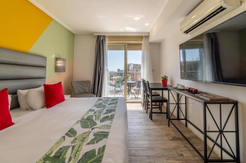a hotel room with a bed and a desk and a balcony at Paamonim Hotel Jerusalem in Jerusalem