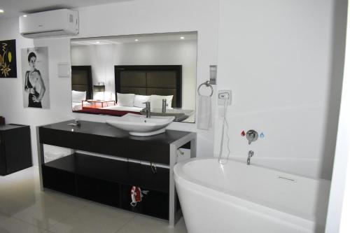 a bathroom with a tub and a sink and a mirror at Spazio Boutique Hotel in Cancún