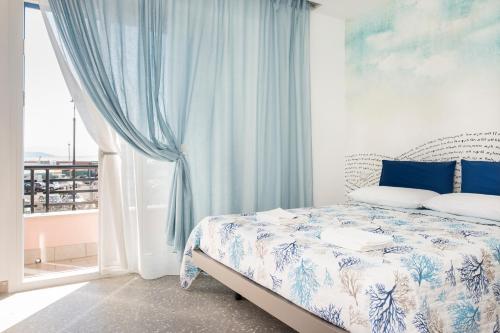 a bedroom with a bed with blue curtains and a window at Acquazzurra Gaeta in Gaeta