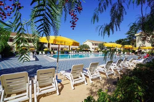 eine Gruppe von Stühlen und Sonnenschirmen neben einem Pool in der Unterkunft Apulia Hotel Sellia Marina in Sellia Marina
